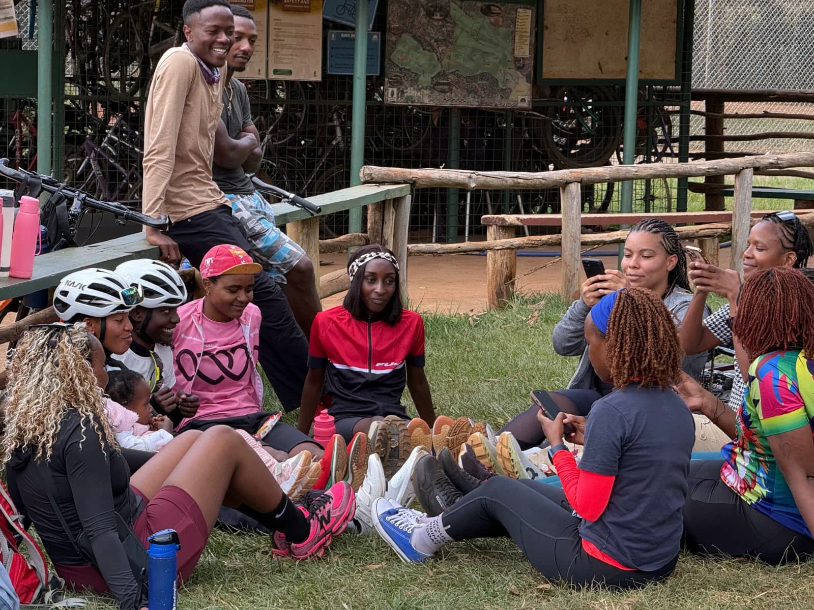 A group of cyclists sitting and standing together beside bicycle racks