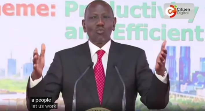 A speaker addressing the National Productivity and Performance Conference from a podium, shown in a television broadcast