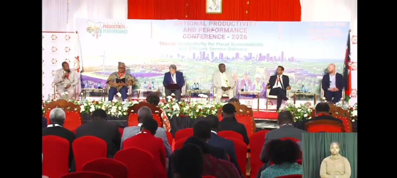 A conference plenary with a panel seated on stage beneath a banner reading National Productivity and Performance Conference 2026