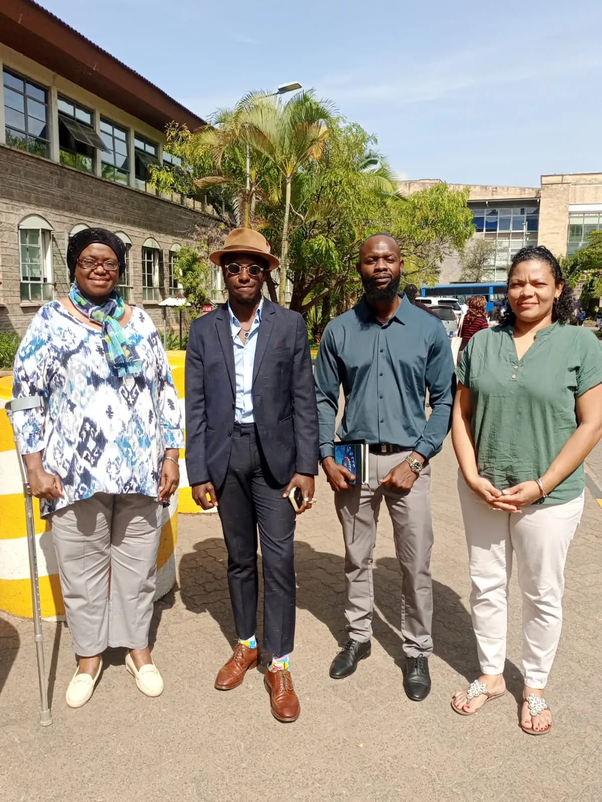 Four people standing together outside an institutional building