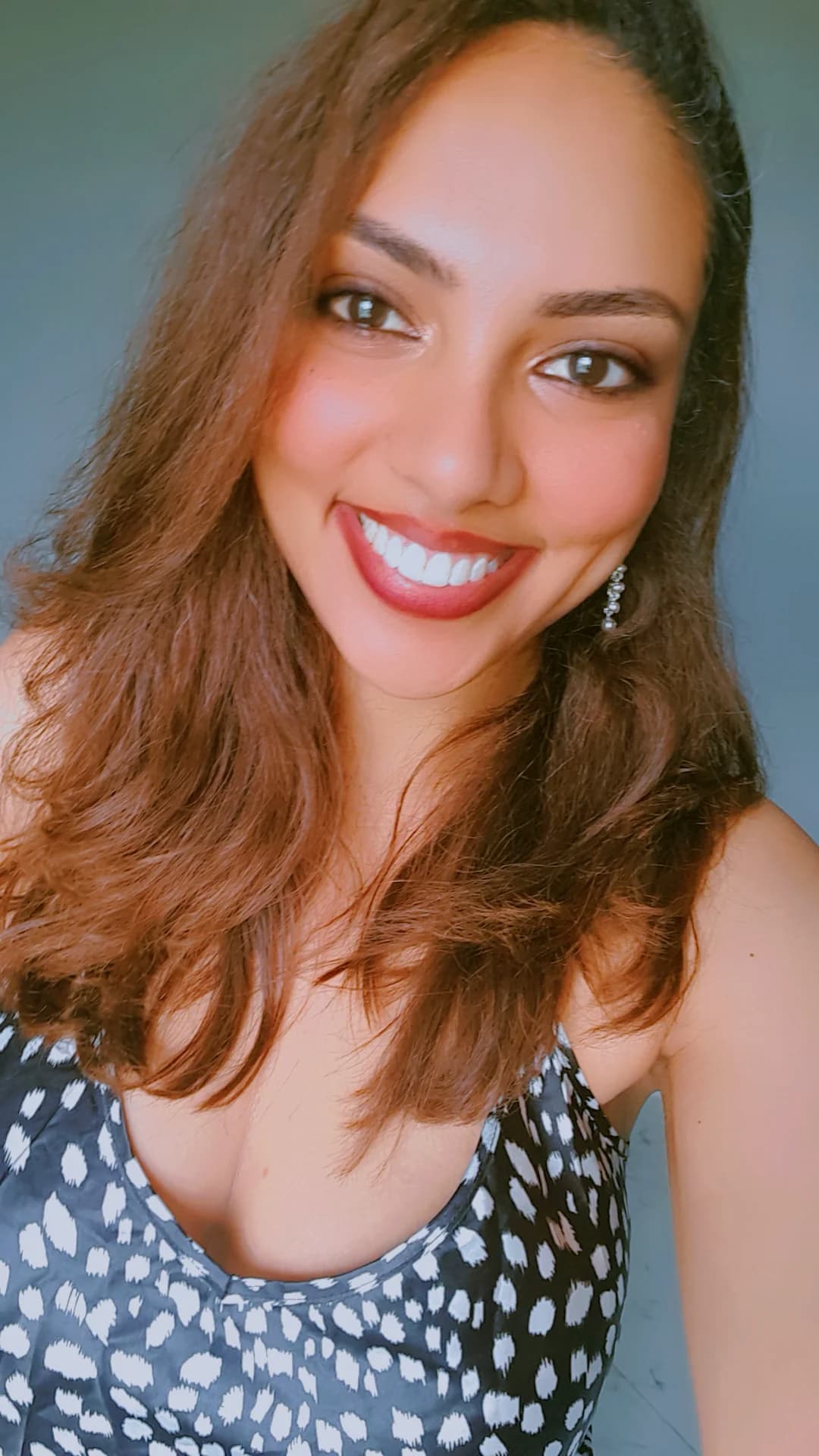 A smiling portrait of a woman wearing a patterned top