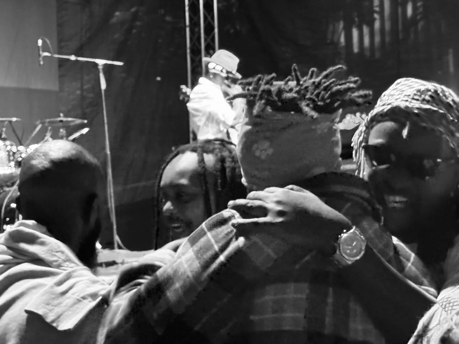 Musicians greeting each other beside the stage after a performance, photographed in black and white
